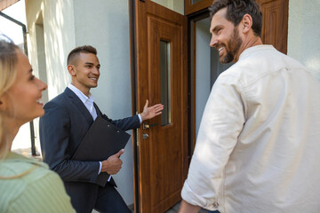 Agent inviting clients to tour new home in suburban setting