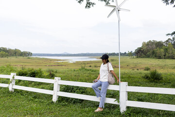 A young woman enjoys a weekend at a scenic café, posing by a rustic cowboy-style fence with...