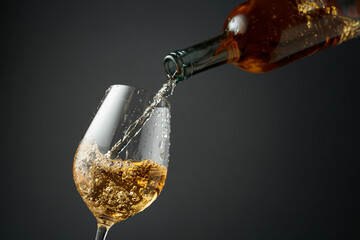 Pouring white wine from a bottle into a glass.