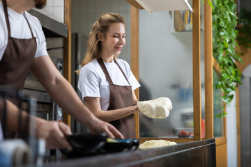 Two bakers focused on dough preparation while working in a bright kitchen