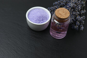 Lavender and lavender oil in bottles on black marble
