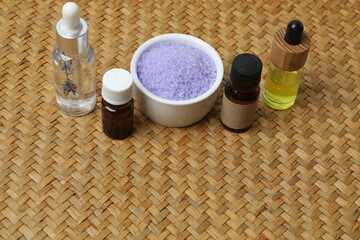 Lavender and lavender oil in bottles on a wicker mat
