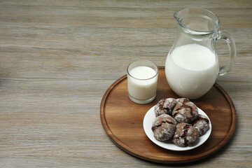 glass and jug with milk, cookies on wooden background