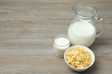 glass and jug with milk, cornflakes on wooden background