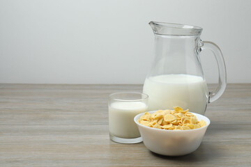 glass and jug with milk, cornflakes on wooden background
