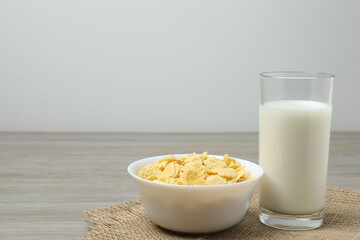 glass with milk, cornflakes on wooden background