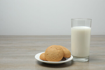 glass with milk and cookies on wooden background