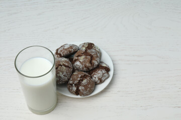 glass with milk and cookies on white wooden background