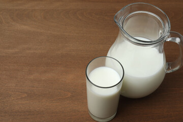 glass and jug with milk on wooden background
