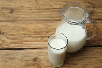 glass and jug with milk on wooden background
