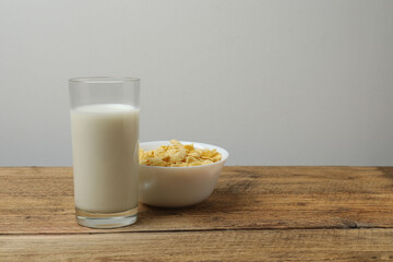 glass with milk, cornflakes on wooden background