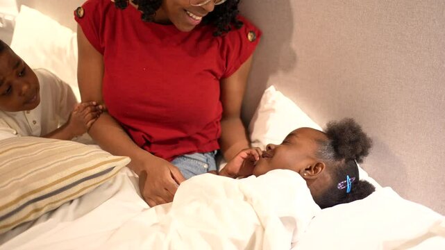 Mom putting her two children to bed in the evening, the girl is already asleep and the boy is still awake