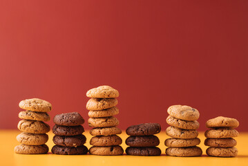 Stacks of Assorted Cookies on Colorful Background, Various Cookie Towers Arranged on Yellow and Red...