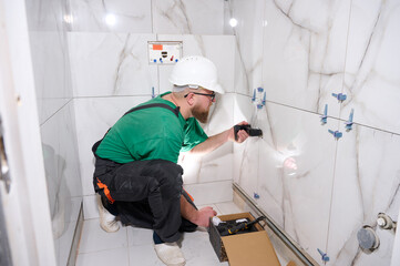 Plumber installing a handheld bidet sprayer. Plumbing for wall mixer. Wall mounted tap or shower...