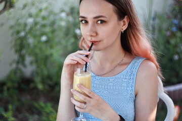 Young Woman in blue dress Enjoying Drink Outdoors