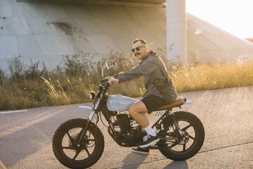 Motorcyclist riding custom motorcycle on country road at sunset