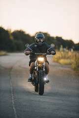 Obraz premium Motorcyclist riding on country road at sunset