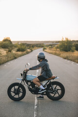 Fototapeta premium Young man riding custom motorcycle on country road