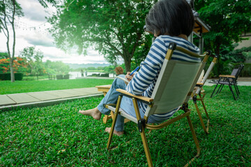Woman enjoying digital detox while reading book in peaceful garden chair surrounded by green nature...