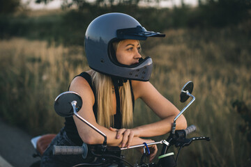 Young blonde woman wearing a protective helmet on a motorcycle