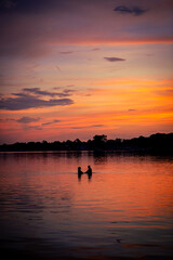 silhouette of a couple enjoying each other's company in the water under an amazing colorful sunset