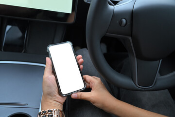 Close up of a person holding smartphone with blank screen while seated in a modern car