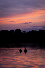 Fototapeta premium silhouette of a couple in the water under an amazing colorful sunset