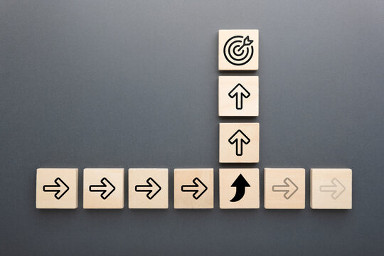 Wooden blocks with arrow icons and target symbol show concept of changing direction, adapting strategy, and focusing on goals for success and growth