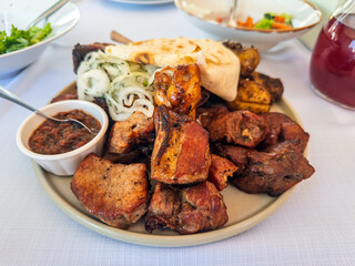 A generous platter of mixed grilled meat, including pork shashlik and chicken, served with rustic roasted potatoes and fresh lavash bread on a restaurant table
