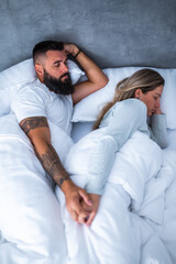 Young married couple is sleeping in their bed. They are holding hands and enjoying good sleep.