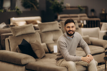 Smiling Man Sitting Comfortably in a Modern Home Furniture Store
