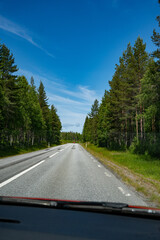 Tarmac road through forest in sweden with blue sky