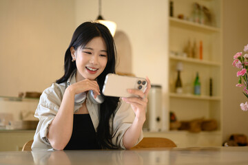 Cheerful woman watching content on smartphone while relaxing at a cozy cafe