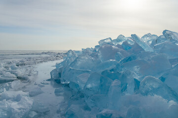 Ice formations glisten under soft sunlight, creating a stunning natural landscape with clear blue...