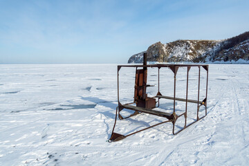 Rusty metal structure stands on frozen surface, surrounded by vast icy landscape and distant rocky...