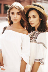 Fashion portrait of two young stylish hippie brunette and blond women models in summer sunny day in...