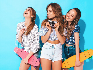 Three young stylish smiling beautiful female with penny skateboards. Women in summer hipster...