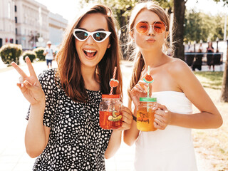 Two young beautiful smiling hipster female in trendy summer clothes and panama hat.Sexy carefree...