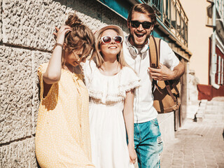 Group of young three stylish friends posing in the street. Fashion man and two cute female dressed...