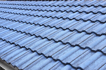 row of grunge blue concrete wavy roof tiles with silver aluminium gutter