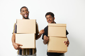 Two African American men joyfully holding cardboard boxes, embracing teamwork and collaboration....