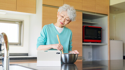 Senior woman cooking while looking at a tablet