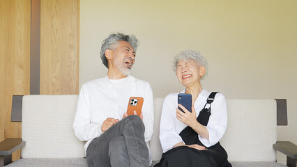 Senior couple laughing together while looking at a smartphone