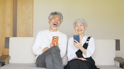 一緒にスマホを見て笑うシニアカップル