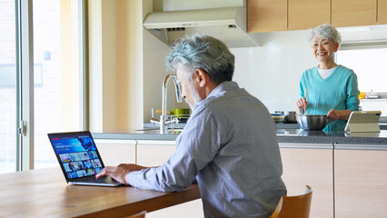 ノートパソコンで動画配信サービスを見るシニア男性