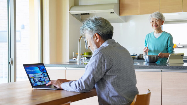 ノートパソコンで動画配信サービスを見るシニア男性