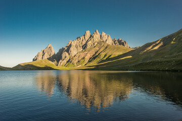 Stunning view of rocky Caucasus mountain peaks reflecting perfectly on a calm alpine lake at...