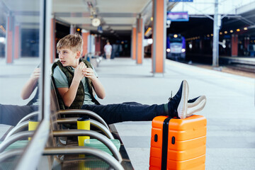 Teen boy looking aside while waiting for next train with luggage
