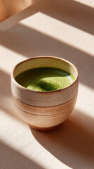 Matcha tea cup with green powder in ceramic mug on wooden table with warm sunlight