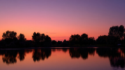 A stunning sunset over a calm lake reflects vibrant colors across the water.